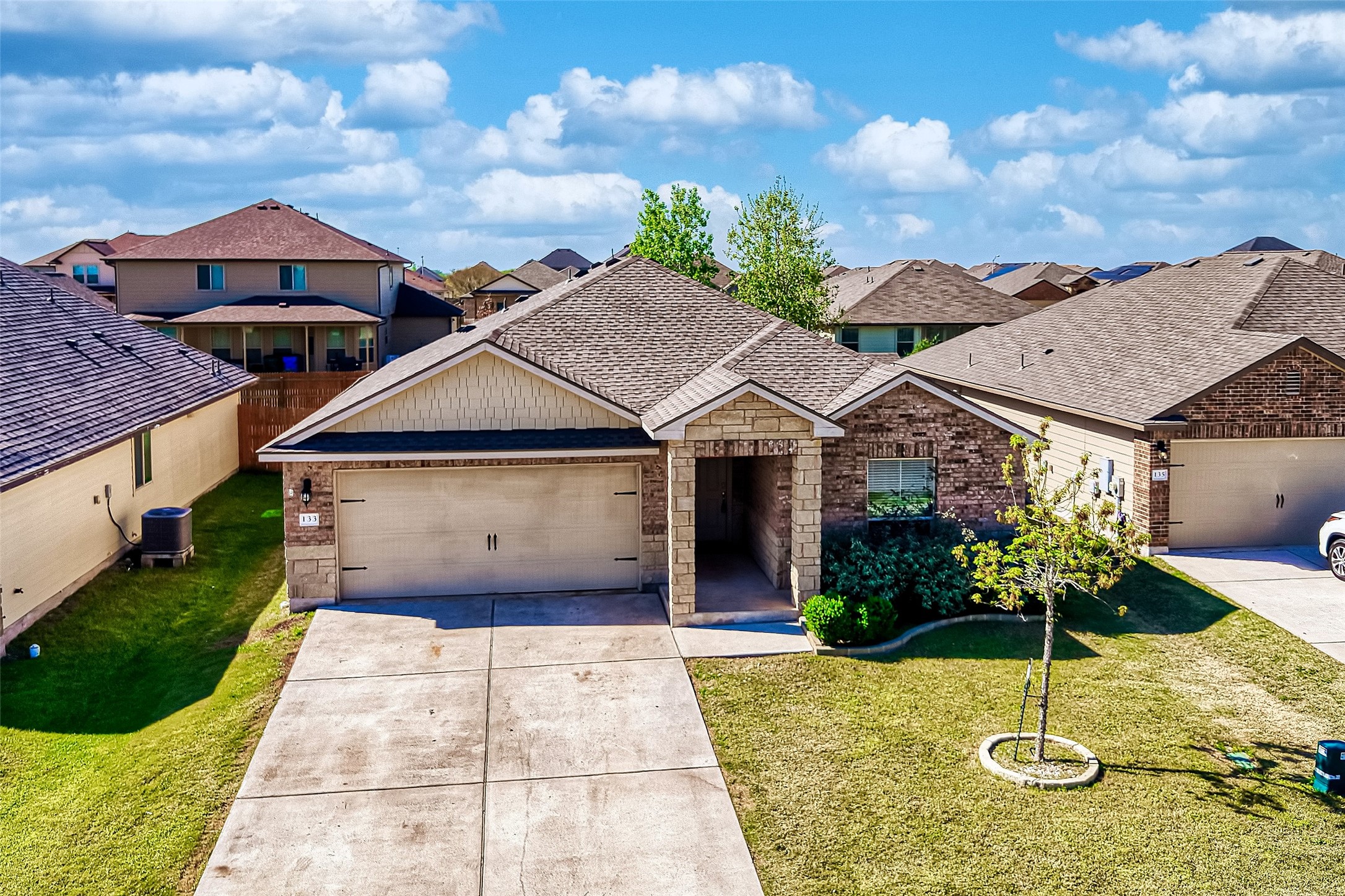 133 Beth Ann Loop Taylor, TX 76574 - Photo 26 of 30 View of front of home featuring a front lawn, a garage, concrete driveway, and a residential view