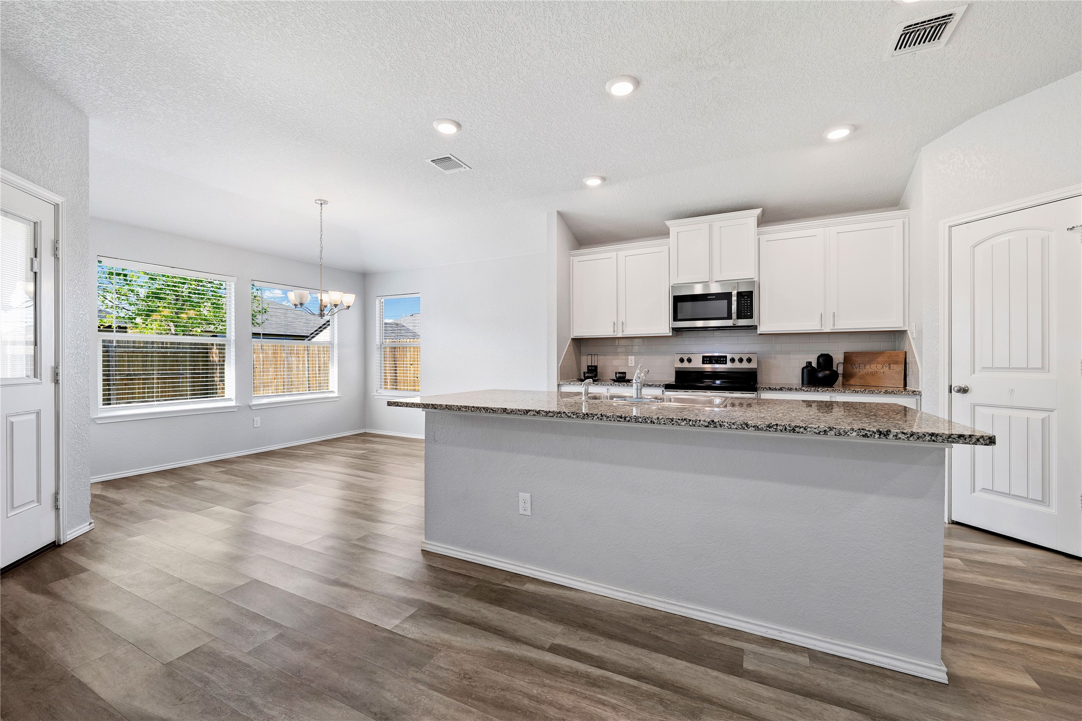 133 Beth Ann Loop Taylor, TX 76574 - Photo 8 of 30 Kitchen featuring white cabinets, hanging lights, light stone countertops, a center island with sink, and dark engineering flooring