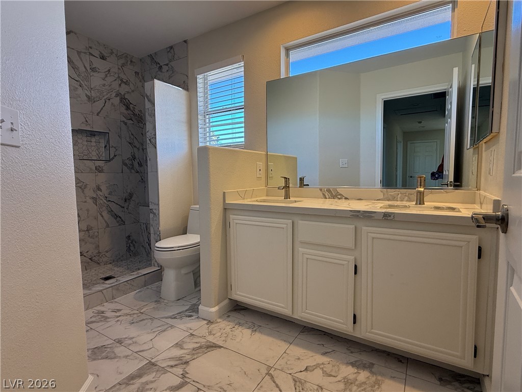 1908 Thunder Ridge Circle Henderson, NV 89012 - Photo 24 of 28 A well-lit bathroom showcases a dual vanity with a generous mirror and a beautifully tiled walk-in shower.