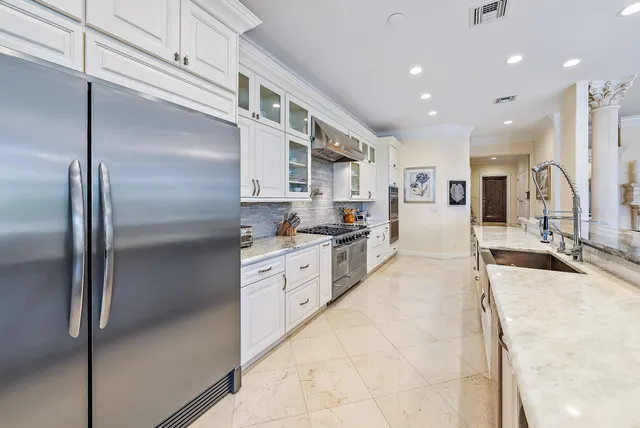 a large kitchen with stainless steel appliances kitchen island granite countertop a refrigerator and a sink