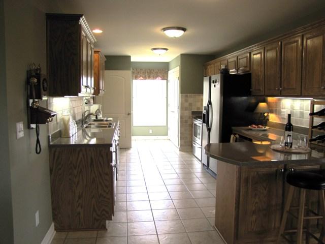 7761 Shoals Branch Road Primm Springs, TN 38476 - Photo 5 of 20 Lovely Kitchen featuring: tile flooring, tile backsplash, stainless steel appliances, lots of cabinet & countertop space, large pantry & laundry room. There is even a computer table built in to the countertop with wiring underneath.
