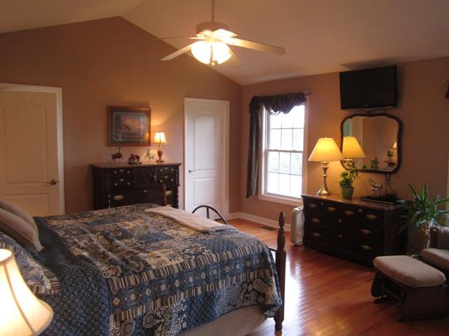 7761 Shoals Branch Road Primm Springs, TN 38476 - Photo 7 of 20 Master Bedroom featuring: glowing hardwood floors, tasteful lighting & walk-in closet. Master Bath has whirlpool tub & tile flooring.
