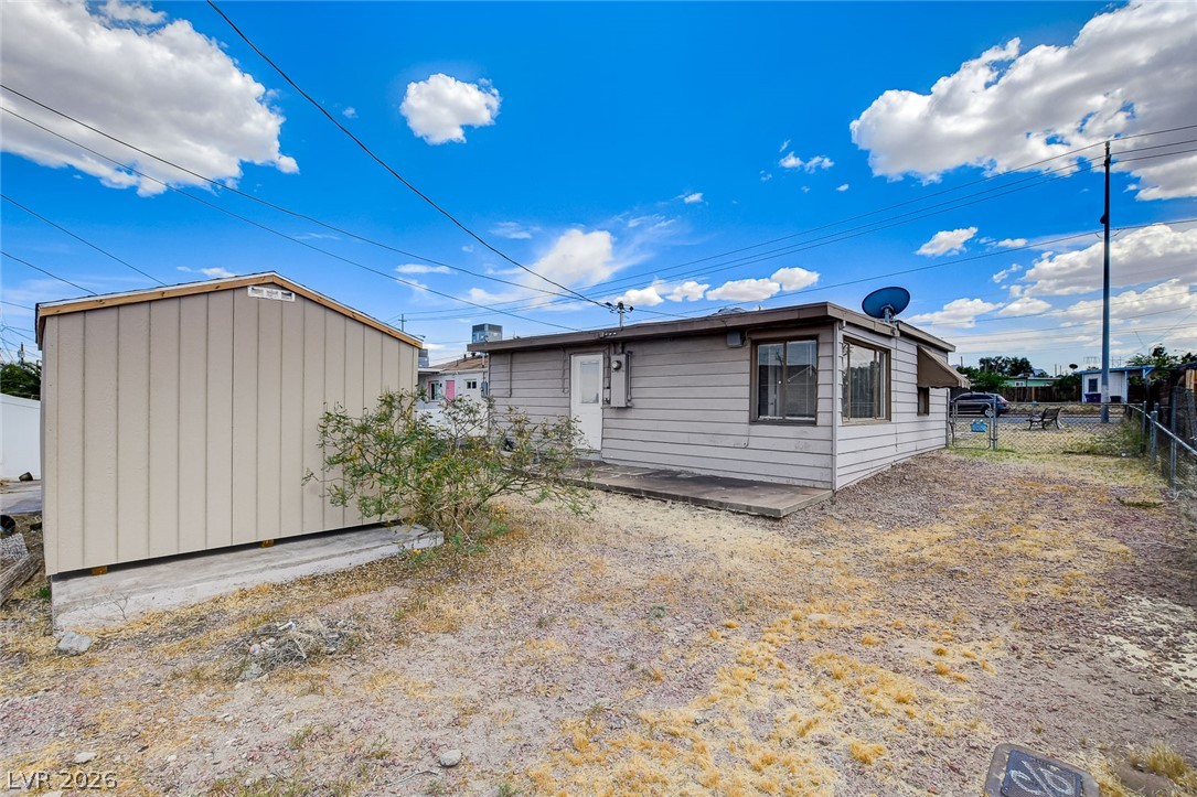 214 West Victory Road Henderson, NV 89015 - Photo 32 of 33 A fenced backyard offers a shed and an additional outdoor building with an awning over a window.