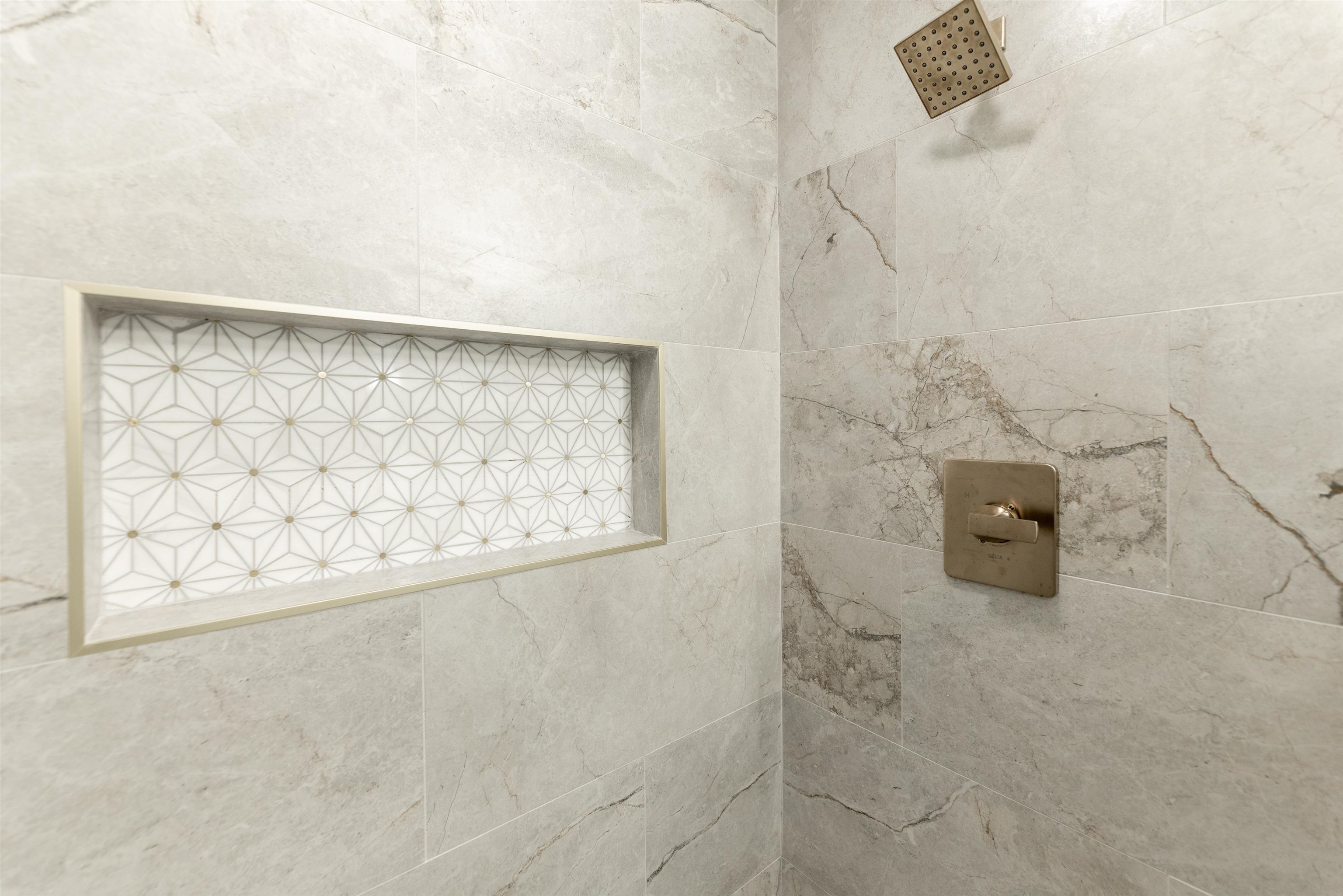 7421 Richmond Road Memphis, TN 38125 - Photo 25 of 39 Shower with large format veined wall tiles, a built-in niche featuring geometric mosaic tile, and a square rain showerhead with coordinating controls