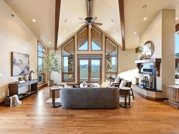 a living room with furniture a large window and wooden floor