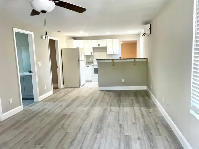 a view of kitchen and empty room with wooden floor
