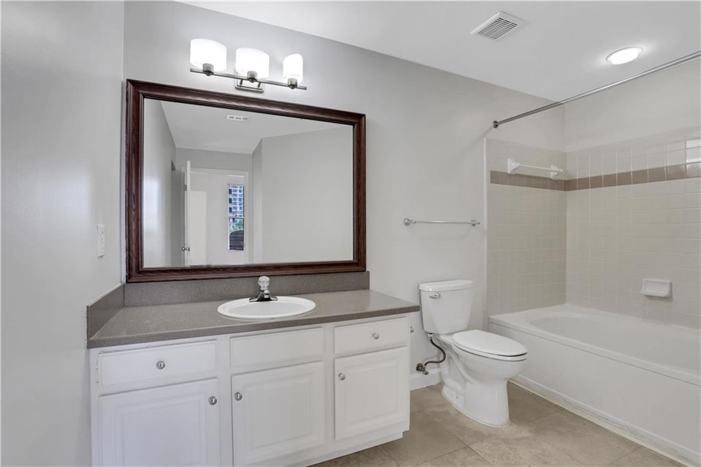 1101 Juniper Street Northeast, Unit 619 Atlanta, GA 30309 - Photo 17 of 28 a bathroom with a granite countertop sink toilet a large mirror a bathtub and shower