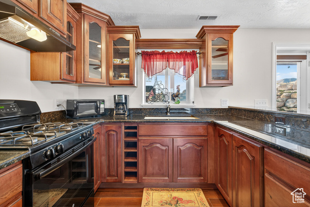 4768 East Hickman Canyon Road Stockton, UT 84071 - Photo 44 of 85 Basement kitchen with gas stove, dark stone countertops, under cabinet range hood, dark wood-style floors.