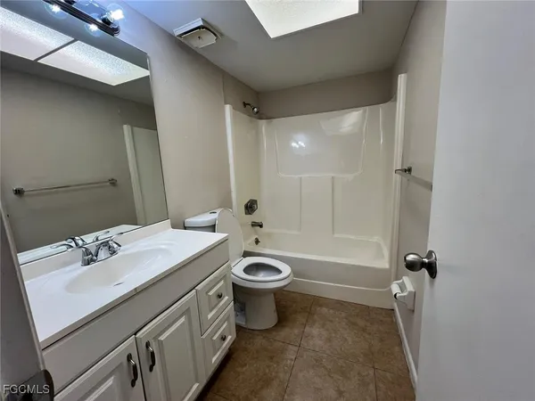 a bathroom with a granite countertop sink a toilet a mirror and shower