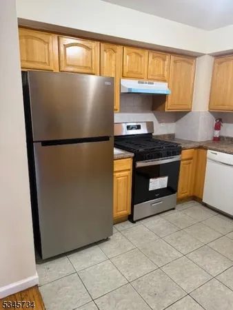 a kitchen with granite countertop a refrigerator a stove a sink and a window