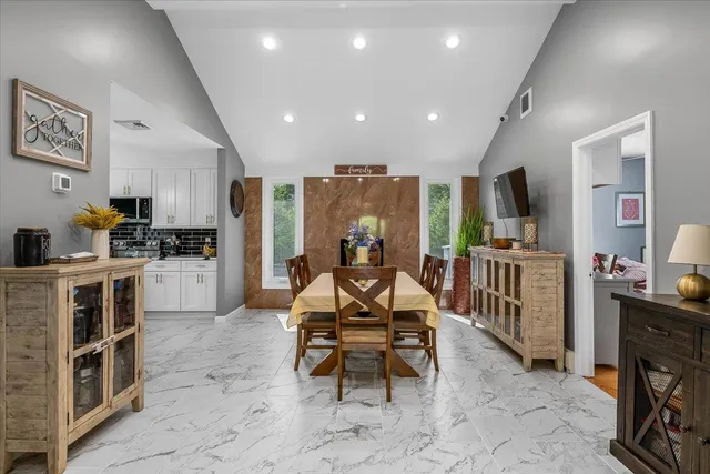 a living room with furniture a flat screen tv and a refrigerator