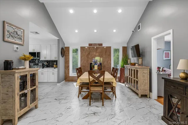 a living room with furniture a flat screen tv and a refrigerator