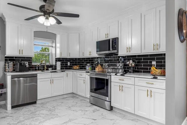 a kitchen with white cabinets granite counter tops and a stove