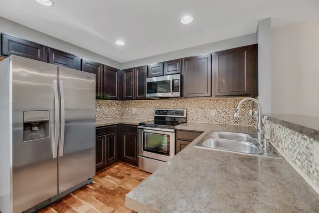 a kitchen with granite countertop a refrigerator stove and microwave
