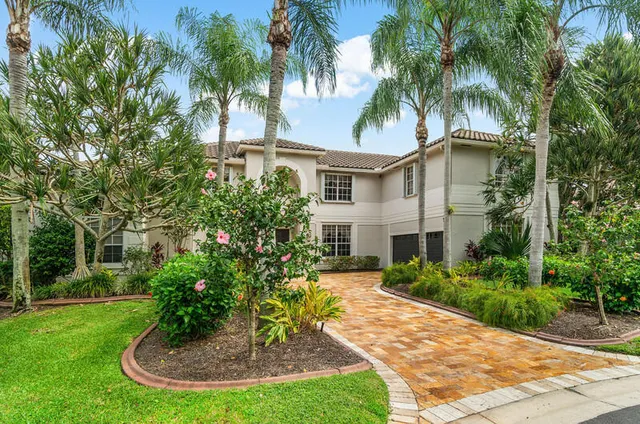 a view of a house with a yard potted plants and palm trees