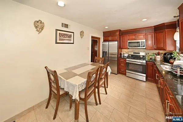 a kitchen with stainless steel appliances granite countertop a stove top oven a sink a dining table and chairs