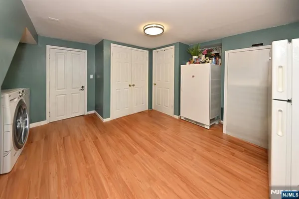 a big room with wooden floor and a refrigerator
