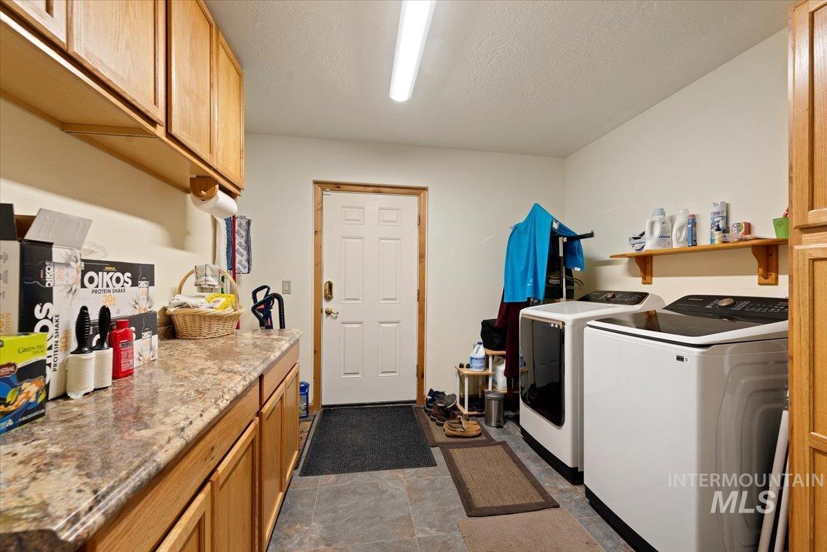 11650 Columbia Road Boise, ID 83709 - Photo 20 of 32 Washroom with cabinet space, separate washer and dryer, a textured ceiling, and dark stone finish floors