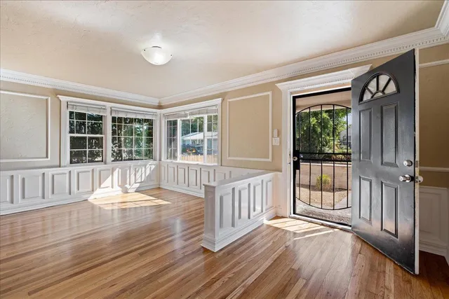 a view of an empty room with wooden floor and a window