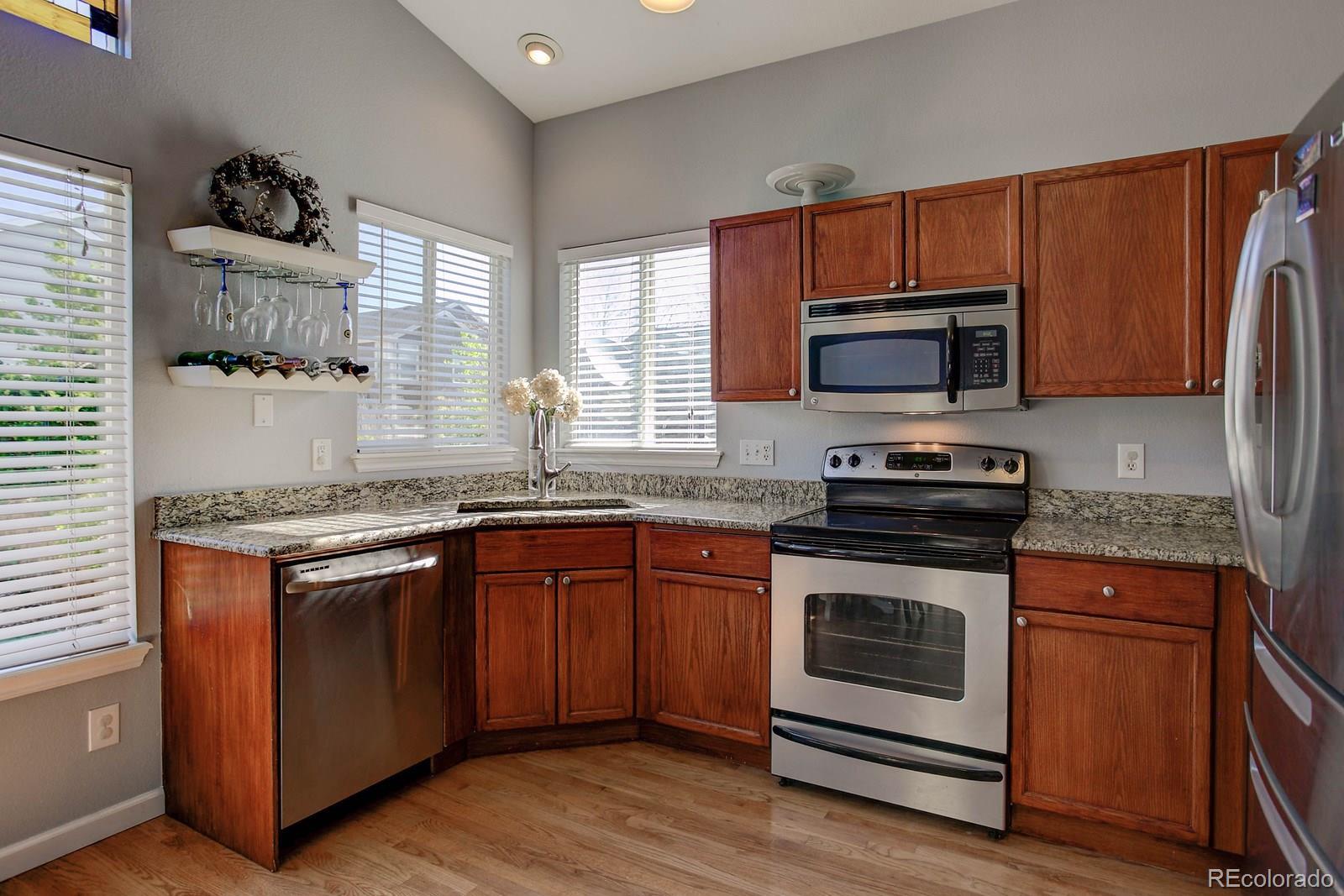 9847 Sydney Lane Highlands Ranch, CO 80130 - Photo 7 of 32 a kitchen with granite countertop wooden cabinets stainless steel appliances and a window