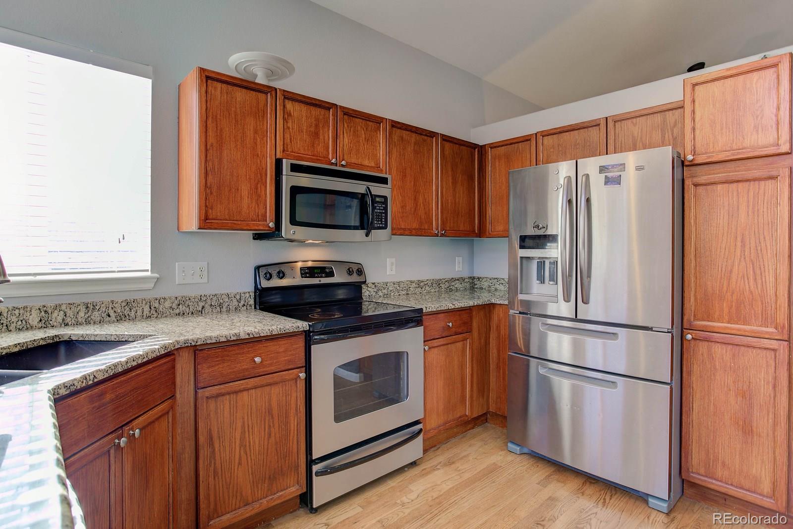 9847 Sydney Lane Highlands Ranch, CO 80130 - Photo 8 of 32 a kitchen with stainless steel appliances granite countertop a refrigerator stove a sink and a microwave