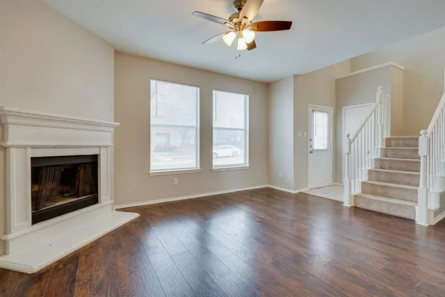 a view of an empty room with wooden floor fireplace and a window