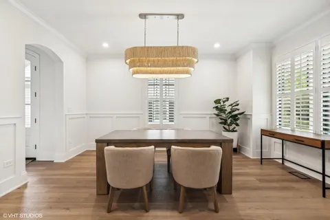 a dining room with wooden floor a chandelier a wooden table and chairs