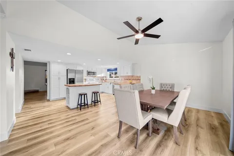 a kitchen with stainless steel appliances kitchen island granite countertop a dining table chairs and a refrigerator