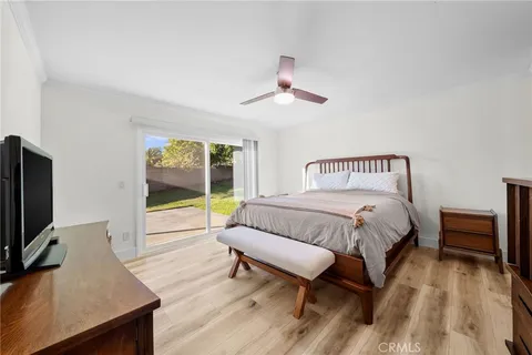 a bedroom with bed a flat tv screen and a dresser