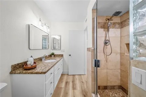 a bathroom with a granite countertop sink a toilet a mirror and shower