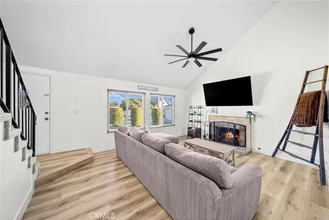 a open kitchen with stainless steel appliances kitchen island a stove a refrigerator a dining table and chairs with wooden floor