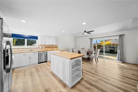 a living room with stainless steel appliances furniture refrigerator and wooden floor