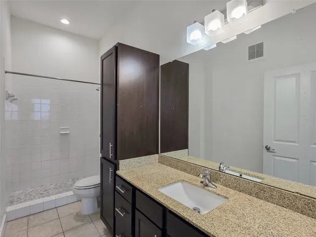 a bathroom with a granite countertop sink a toilet and shower