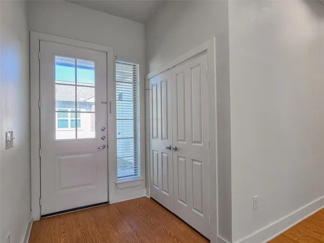 an empty room with wooden floor closet and windows
