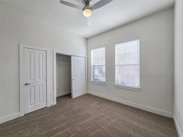an empty room with chandelier fan and windows