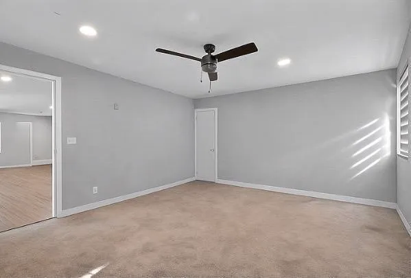 an empty room with a ceiling fan and window
