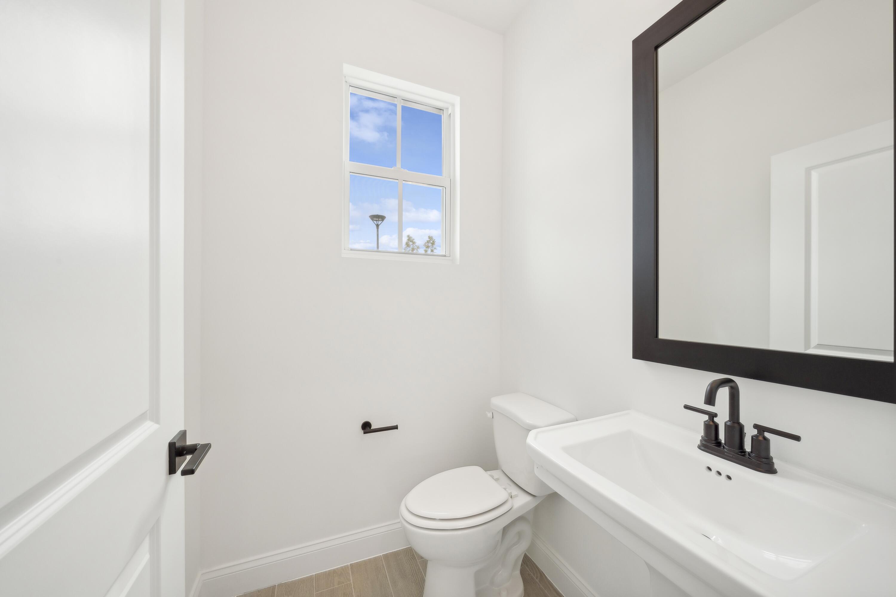 171 Southeast Birch Terrace, Unit 740 Stuart, FL 34997 - Photo 11 of 30 a bathroom with a toilet a sink and mirror