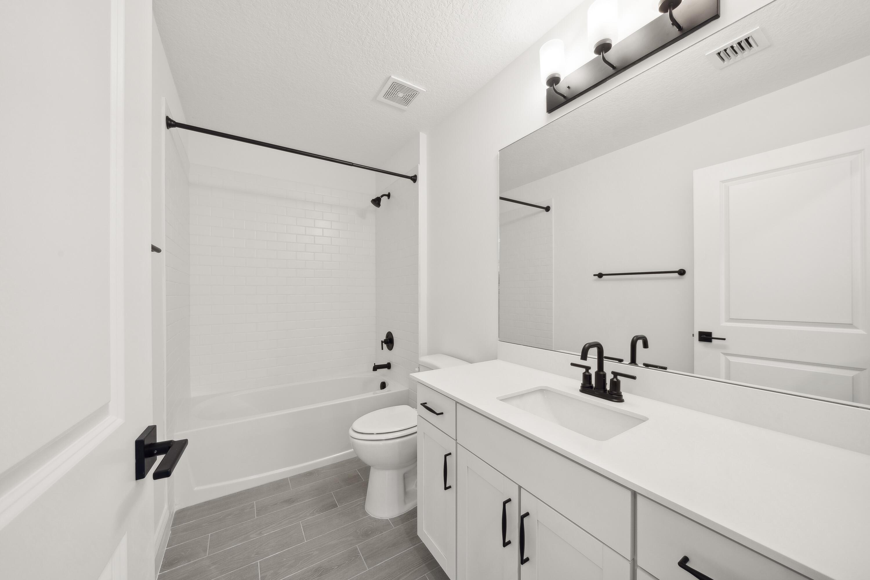 171 Southeast Birch Terrace, Unit 740 Stuart, FL 34997 - Photo 19 of 30 a bathroom with a double vanity sink a toilet and a tub