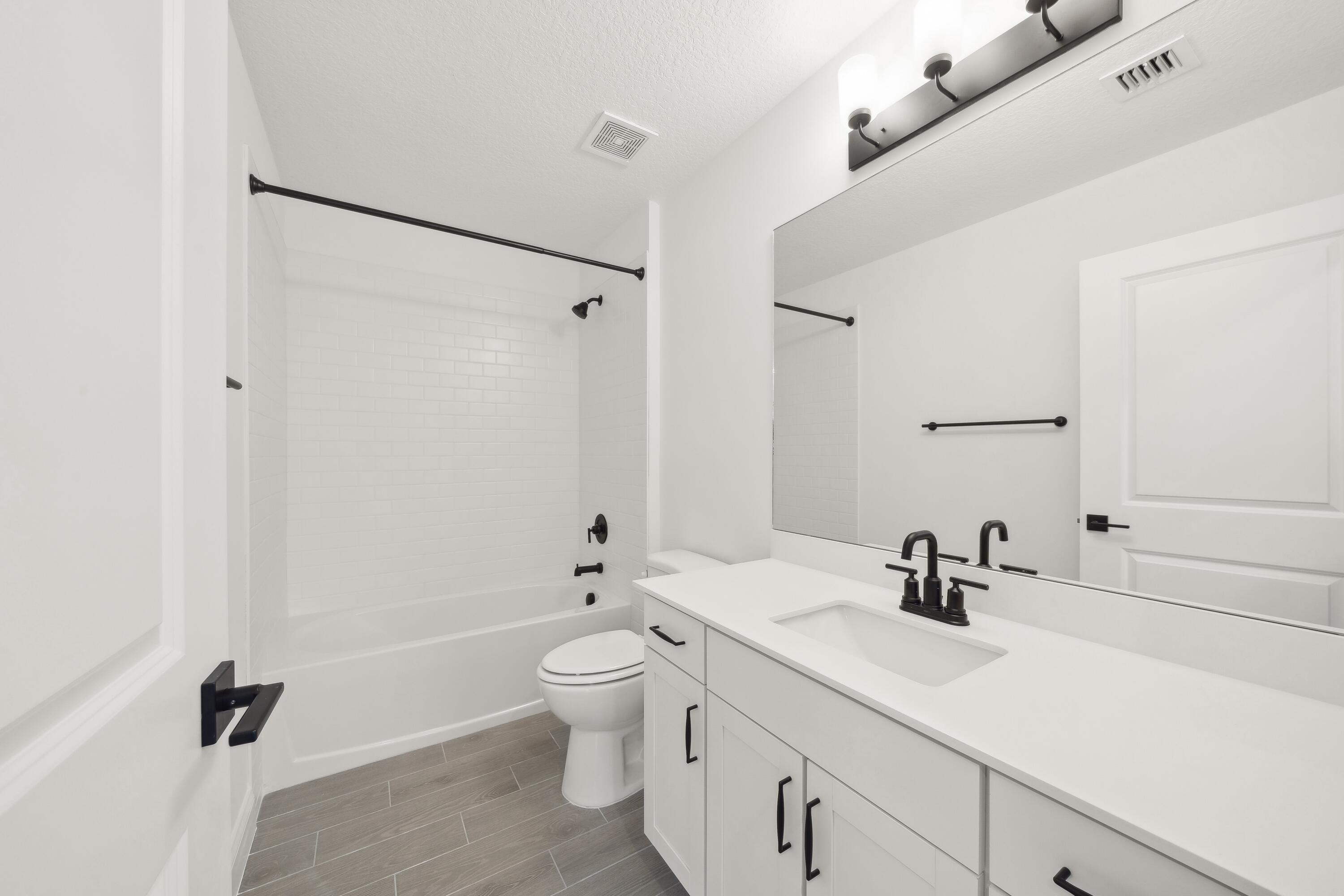 171 Southeast Birch Terrace, Unit 740 Stuart, FL 34997 - Photo 20 of 30 a bathroom with a double vanity sink a toilet and a tub