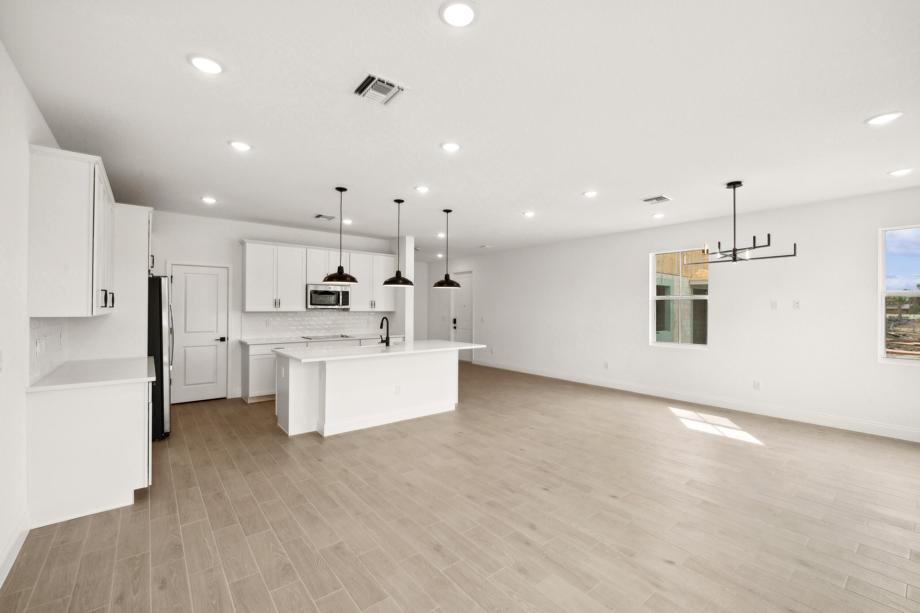171 Southeast Birch Terrace, Unit 740 Stuart, FL 34997 - Photo 8 of 30 a large white kitchen with kitchen island a sink a center island stainless steel appliances and a counter top space