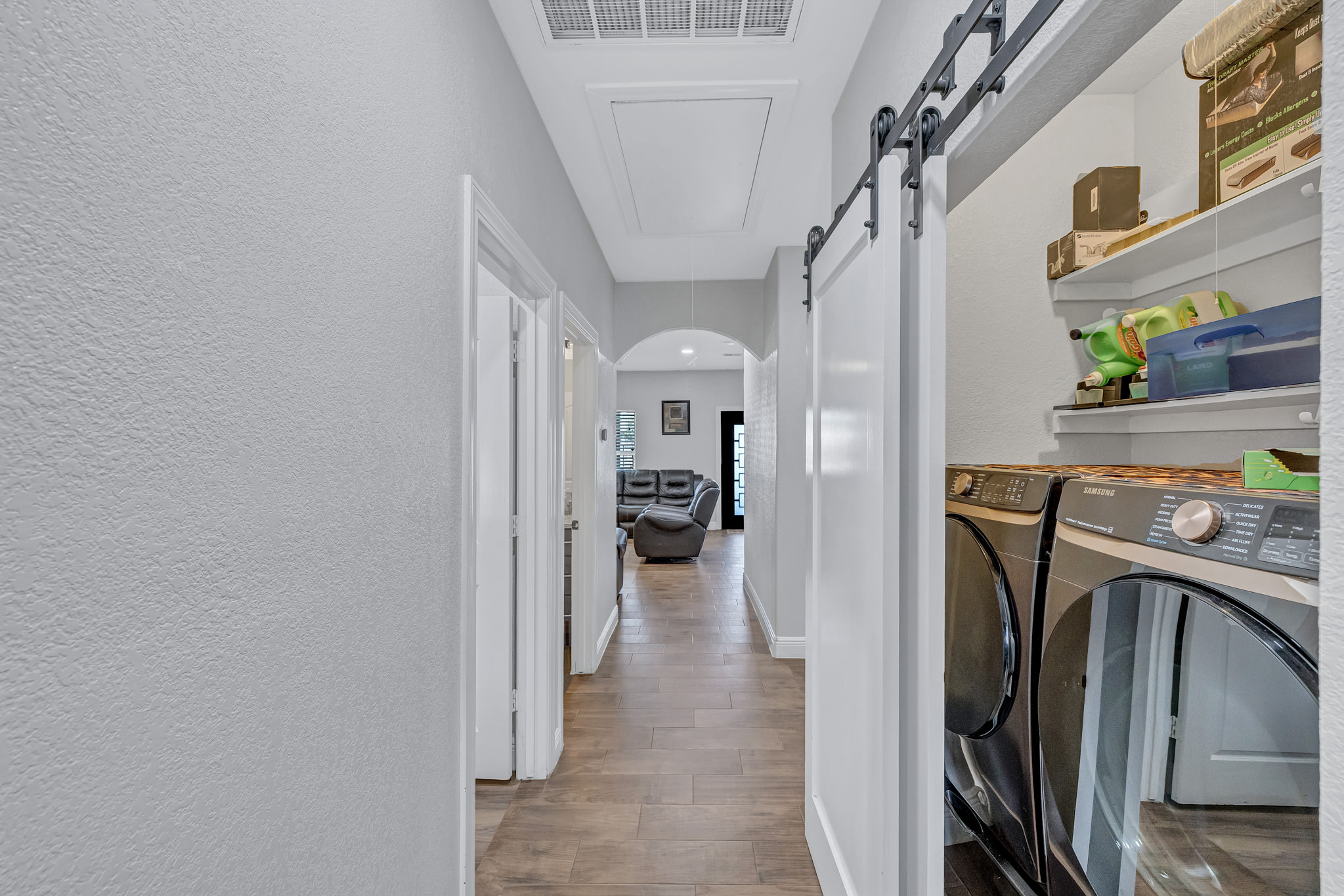 421 Las Lomas Drive Elgin, TX 78621 - Photo 13 of 30 Laundry area with a barn door, a textured wall, light wood-style flooring, washer and clothes dryer, and arched walkways