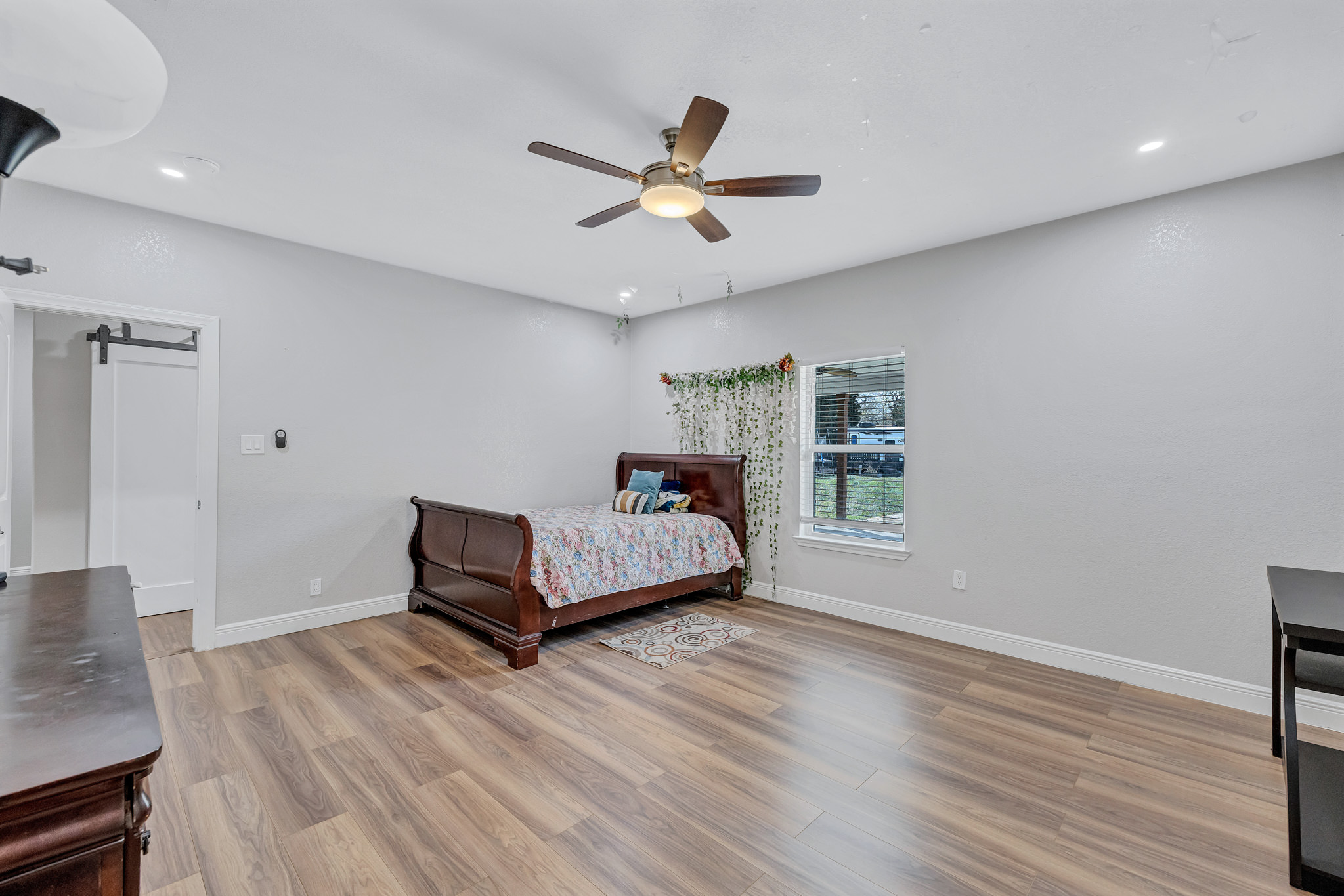 421 Las Lomas Drive Elgin, TX 78621 - Photo 16 of 30 Bedroom with a barn door, light wood-style floors, ceiling fan, and recessed lighting