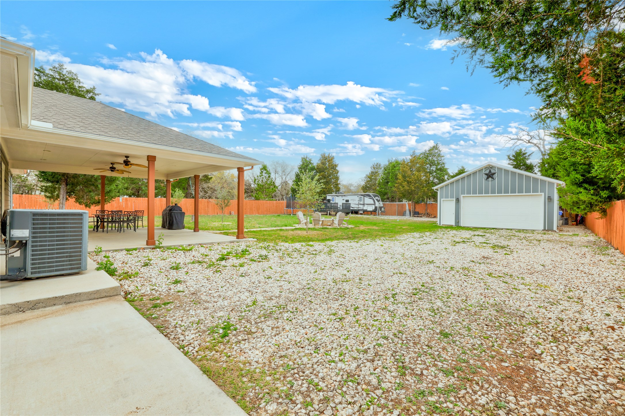 421 Las Lomas Drive Elgin, TX 78621 - Photo 27 of 30 Fenced backyard featuring a patio area, a ceiling fan, an outbuilding, a detached garage, and outdoor dining space