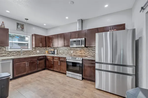 a kitchen with stainless steel appliances granite countertop a refrigerator stove top oven and sink