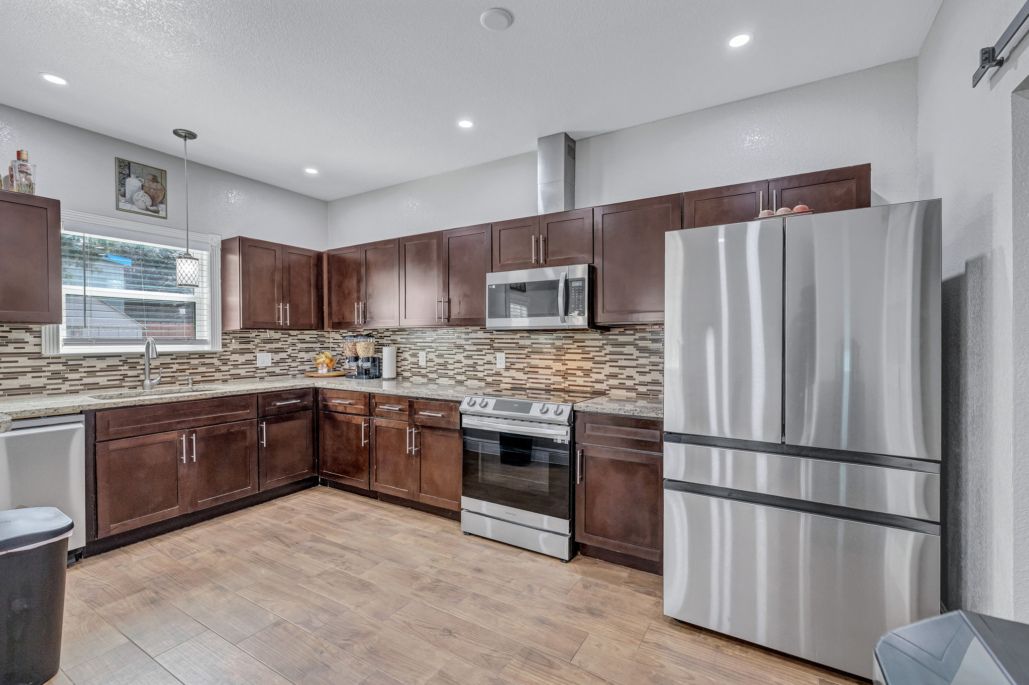 421 Las Lomas Drive Elgin, TX 78621 - Photo 4 of 30 Kitchen featuring stainless steel appliances, light wood-type flooring, dark wood finish cabinetry, and light stone countertops