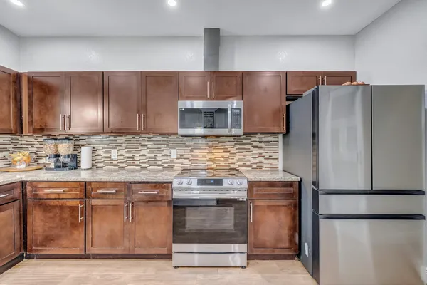 a kitchen with granite countertop a refrigerator and a stove top oven