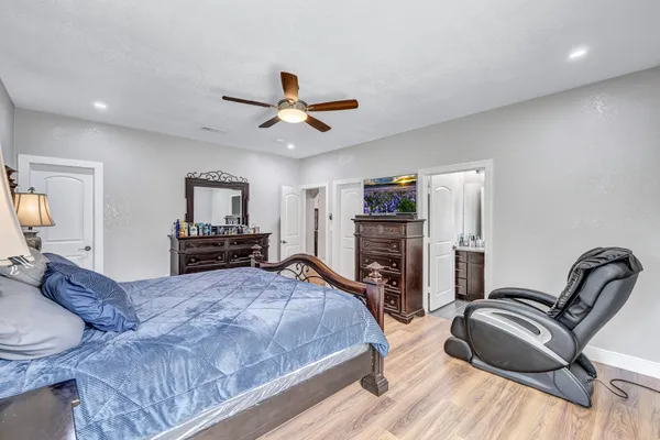 a bedroom with bed a flat tv screen and a dresser