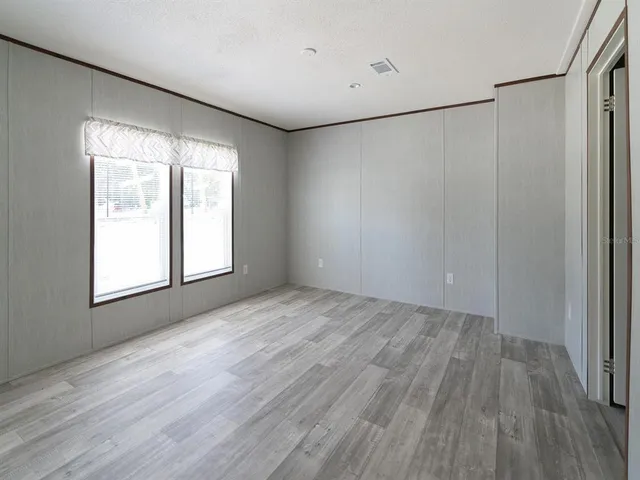 an empty room with wooden floor and windows with curtains