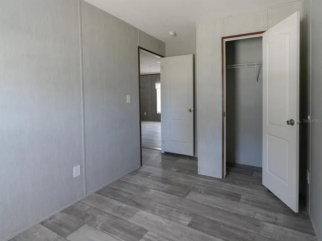 a view of an empty room with wooden floor and a bathroom