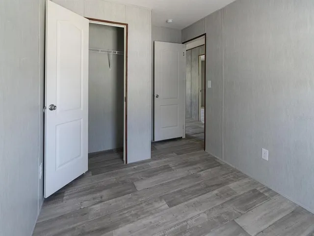 a view of an empty room with wooden floor and closet